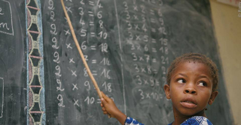 Child pointing at chalkboard Sicao