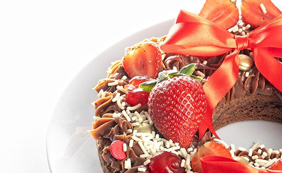 brownie de chocolate redondo com granulados de chocolate branco em cima e morangos